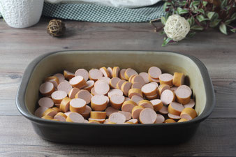 Currywurst in Stücken geschnitten in die Ofenhexe von Pampered Chef verteilen