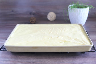 Pudding auf den vorgebackenen Teig verteilen und Pfirsiche auflegen