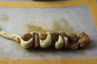 Spieße mit Fleisch und Brezenteig stecken