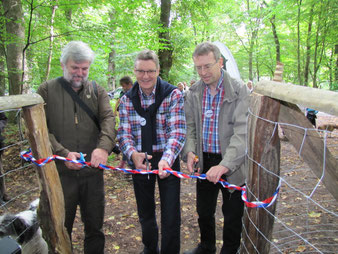 (v.li.) Knut Sturm vom Stadtwald Lübeck, Senator Bernd Möller und Holger Lindberg vom Hunde-Freilauf-Lübeck zerschneiden das Eröffnungsband.