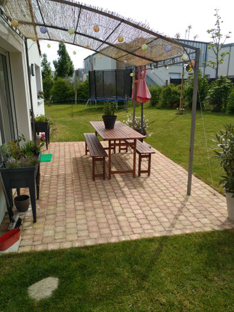 Il s'agit d'une terrasse en pavés design contemporain et modern dans un jardin  avec pergolas bois, gazon, pelouse, haie, arbres, arbustes, potager, clôture acier à saint julien de concelles, Divatte sur Loire, Haute Goulaine, Vertou , Loroux bottereau