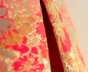 Bild und Button um Zugang zur Untereseite 'Meine Arbeit' zu erhalten. Das Bild zeigt einen vergösserten Ausschnitt einer STofffalte. Der Stoff ist ein mit gold verzierter pinker Jacquard