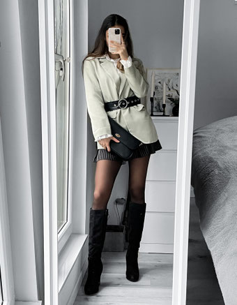 Outfit for winter. Wearing black suede boots, with a stripped black skater skirt, an oversized pastel green blazer, black belt and black clutch bag.
