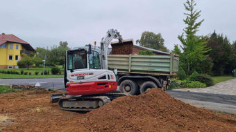 Takeuchi Minibagger belädt LKW auf Baustelle in Hessen