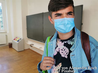 Schüler mit Maske vor Schultafel