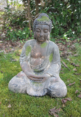 Buddha Statue groß mit Moos bewachsen in Garten auf Wiese