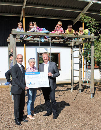 Bei der Spendenübergabe: Stefan Kunz, Barbara Itschner und Thomas Birkenmaier (v.l.) vor dem Klettergerüst mit Kindern