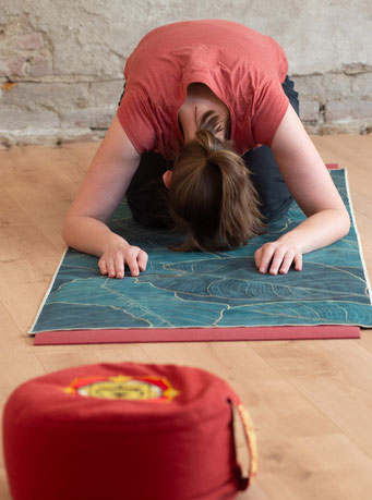 Christina mit Yogakissen uund Matte in knieender Vorbeuge