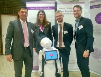 Prof. Dr. Michael Vilain, Carmen Schulz, Dr. Matthias Heuberger und Tobias Meyer (alle IZGS der EHD) begrüßen den intelligenten Roboter Pepper auf dem Social Talk 2017 © Sabine Schlitt, EKKW