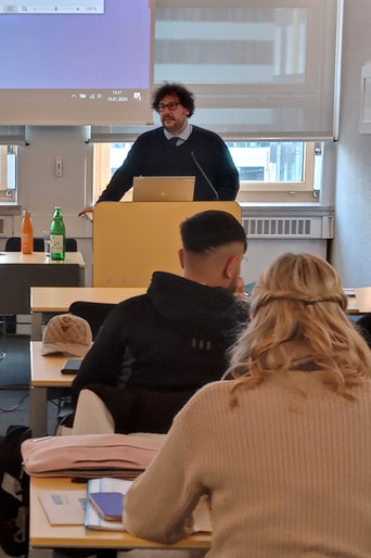 Vortragende stellt Projektinhalte vor – Teilnehmer:innen hören aufmerksam zu