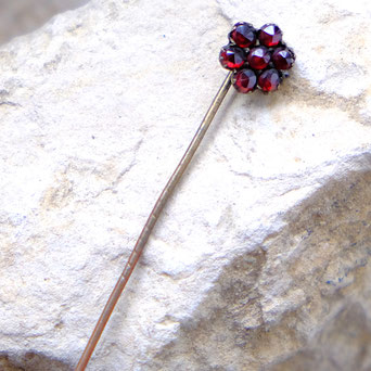 photo of garnet stick pin laying on stone