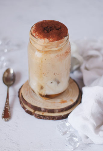 frappè all caffè in ghiaccio adagiato su portabicchieri di legno e accompagnati da cucchiaino in argento e panno bianco