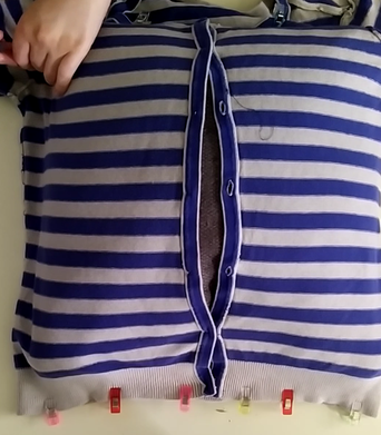 Ein Kissen wird in die Strickjacke gesteckt.