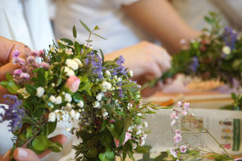 Ein Blumenkranz für die Haare wird aus Blüten und Zweigen gebunden.