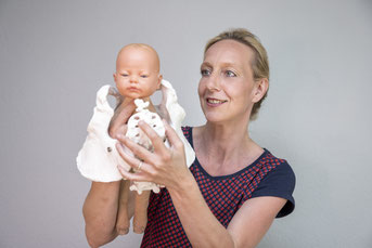 Hebamme Katharina Jeschke zeigt am Beckenmodell, wie der Kopf des Babys geboren wird.