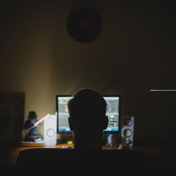 Ein Mann sitzt im Dunkeln vor einem Computerbildschirm