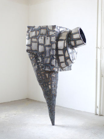 zeitgenössische Skulptur von Andreas Jonak, aus metallplatten zusammengeschweite Kubische form mit zylindrischem Fuße, nur an einem Punkt mit dem Boden verbunden, netzartige Schweißnähre über die ganze Oberfläche verteilt