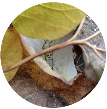 Kleines handgemaltes Bild hinter Blättern