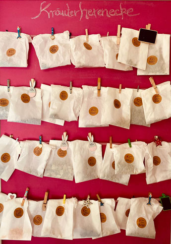 Papiertütchen mit getrockneten Kräutern zur Herstellung von Kräutertees an einer Wand.