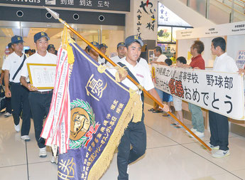 優勝旗を掲げ帰島した八重山高校野球部のメンバー=12日夜、石垣空港