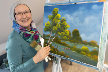 Künstlerin Andrea Christiane Spring mit einem Landschaftsbild an der Staffelei