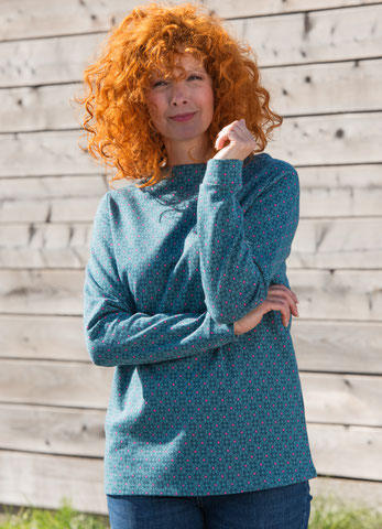 Die Frau trägt ein lanrmiges Shirt asu der kollektion Abneta in der Fareb meergrün mit kleinen Punkten in der Farbe anemone.