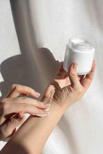 Belles mains d'une femme s'appliquant de la crème naturelle au Miel de Manuka de Nouvelle-Zélande fait maison sur son avant bras avec un arrière plan clair