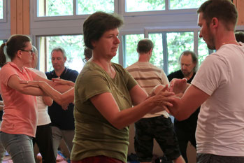 Taiji-Gruppe, die Partnerübungen (Pushing-Hands, Tuishou) bei einem Workshop trainiert.