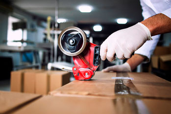 Fulfillment-Mitarbeiter verschließt ein Paket mit einem Klebestreifen