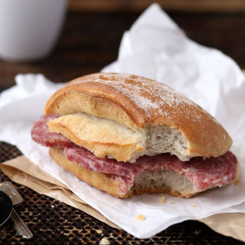 Ein angebissenes Küster-Brötchen mit dicken Stracke-Scheiben liegt auf Backpapier