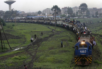 I passeggeri cavalcano le carrozze sovraccariche di un treno di pendolari nella capitale del Kenya, Nairobi