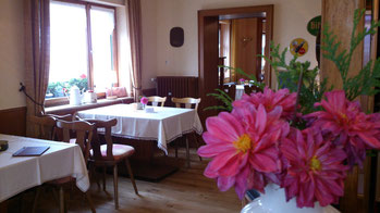 Café Innenraum mit Tischen und Stühlen. Blumen im Vordergrund.