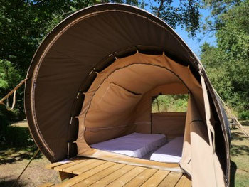 photo d'une cabane en toile pour camping étape, parfait pour cycliste ou motards qui n'ont pas de tente. On y voit la tente sur pilotis et la vraie literie à l'intérieur.