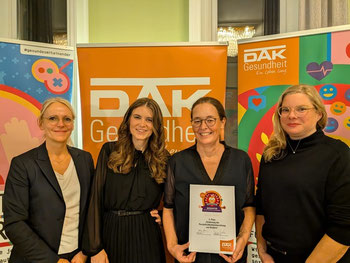 Gruppe von weiblichen Preisträgerinnen von MUS-E posiert vor DAK Logo