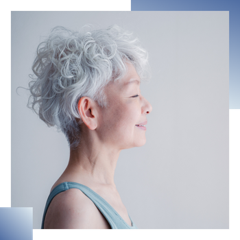 白髪のショートカールヘアの女性の横顔。穏やかな表情で目を閉じ、微笑んでいます。