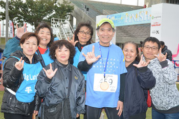 神奈川県からフルマラソンに出場した榎本さん(中央)を支えた手話通訳ボランティアのスタッフら=22日午後、石垣市中央運動公園陸上競技場