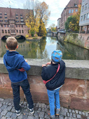 Zwei Jungs stehen nebeneinander auf einer Brücke, mit dem Rücken zur Kamera, und schauen auf die Pegnitz
