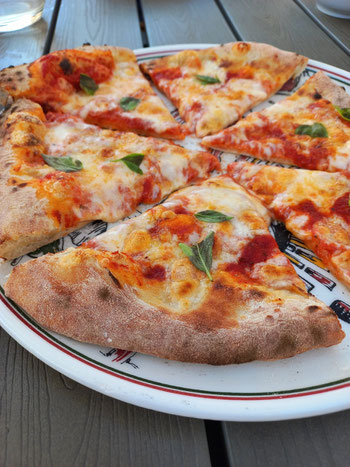 Ein Teller mit elbstgemachter Pizza Margherita steht auf dem Tisch