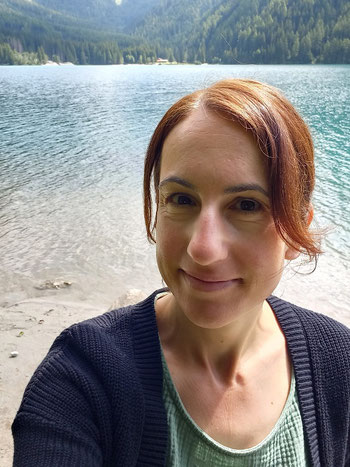 Michaela Dauscher steht am Antholzer See und lächelt in die Kamera für ein Selfie