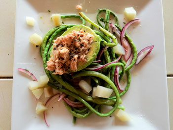 Avocado stuffed with tuna on a bed of long green beans