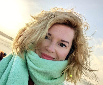 Foto am Strand von Sarah Esslinger-Dahlmann, blonde vom Wind verwehte Haare, grüner Schal, Blick in die Kamera