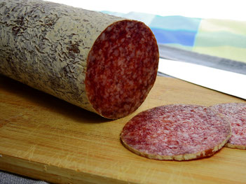 Salami die teilweise aufgeschnitten ist auf einem Holzbrett