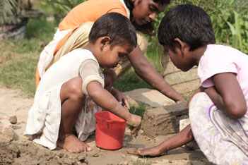 Children working with clay and bricks to build little houses