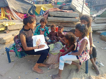 Les «grands» font la lecture aux plus jeunes dehors.