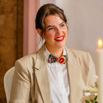 Elegante bunte Damenfliege zu einem weißen Hemd und einem beigen Blazer getragen