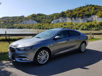 Opel Insignia gris foncé (voiture type limousine) devant les blanches falaises des boucles de la Seine Normande