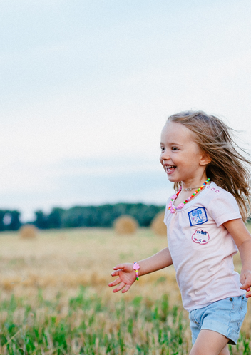 petite fille qui rigole dans un champ astrothérapie thème astral enfant Coaching astrologique pour enfants Analyse astrologique familiale Séance d’astrothérapie parent-enfant Coaching familial en astrologie Comprendre les enfants avec l’astrologie 