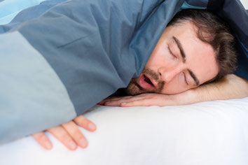 Schlafender schnarchender Mann unter einer Decke