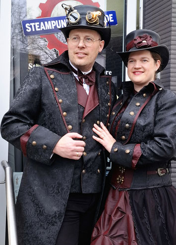 Brautpaar im Steampunk-Partnerlook mit elegantem Hochzeitskleid und passendem Bräutigam-Anzug vor der Hochzeit