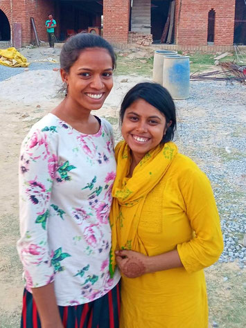 Pooja and Pooja standing in front of the new school building (educators of damini kindergarten)